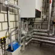 Heizungsmodernisierung Schifferstadt – Vitodens 200-W Wandhängendes Gas-Brennwertgerät Vitodens 200-W nach Heizungsmodernisierung in Schifferstadt, darunter gedämmte Heizungsrohre und blaue Kondensathebeanlage