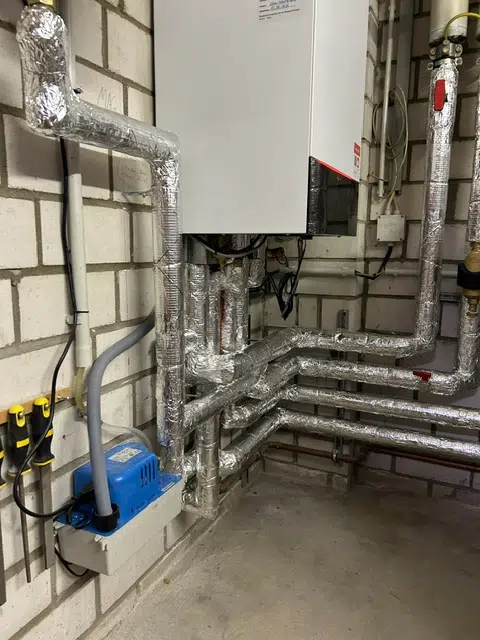 Wandhängendes Gas-Brennwertgerät Vitodens 200-W nach Heizungsmodernisierung in Schifferstadt, darunter gedämmte Heizungsrohre und blaue Kondensathebeanlage